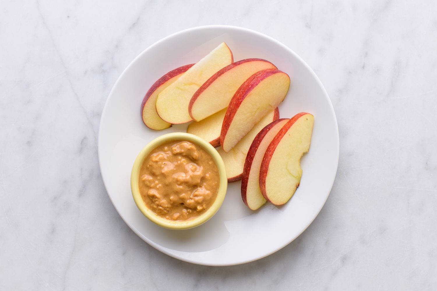 appelschijfjes en dikke pindakaas op een bord