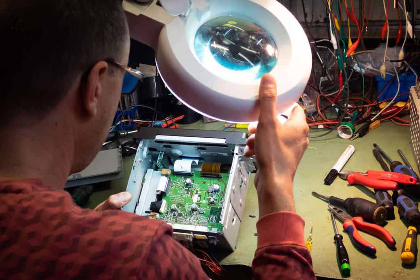 Een andere man inspecteert een elektronisch voorwerp met behulp van een lamp