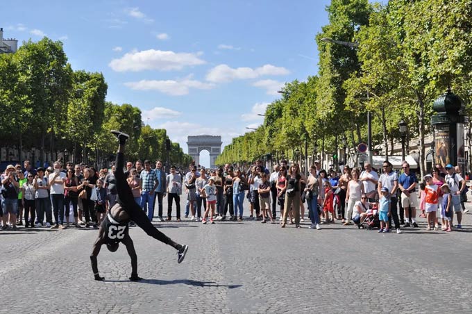 Een man handopstanden voor een menigte in het midden van een straat in Parijs