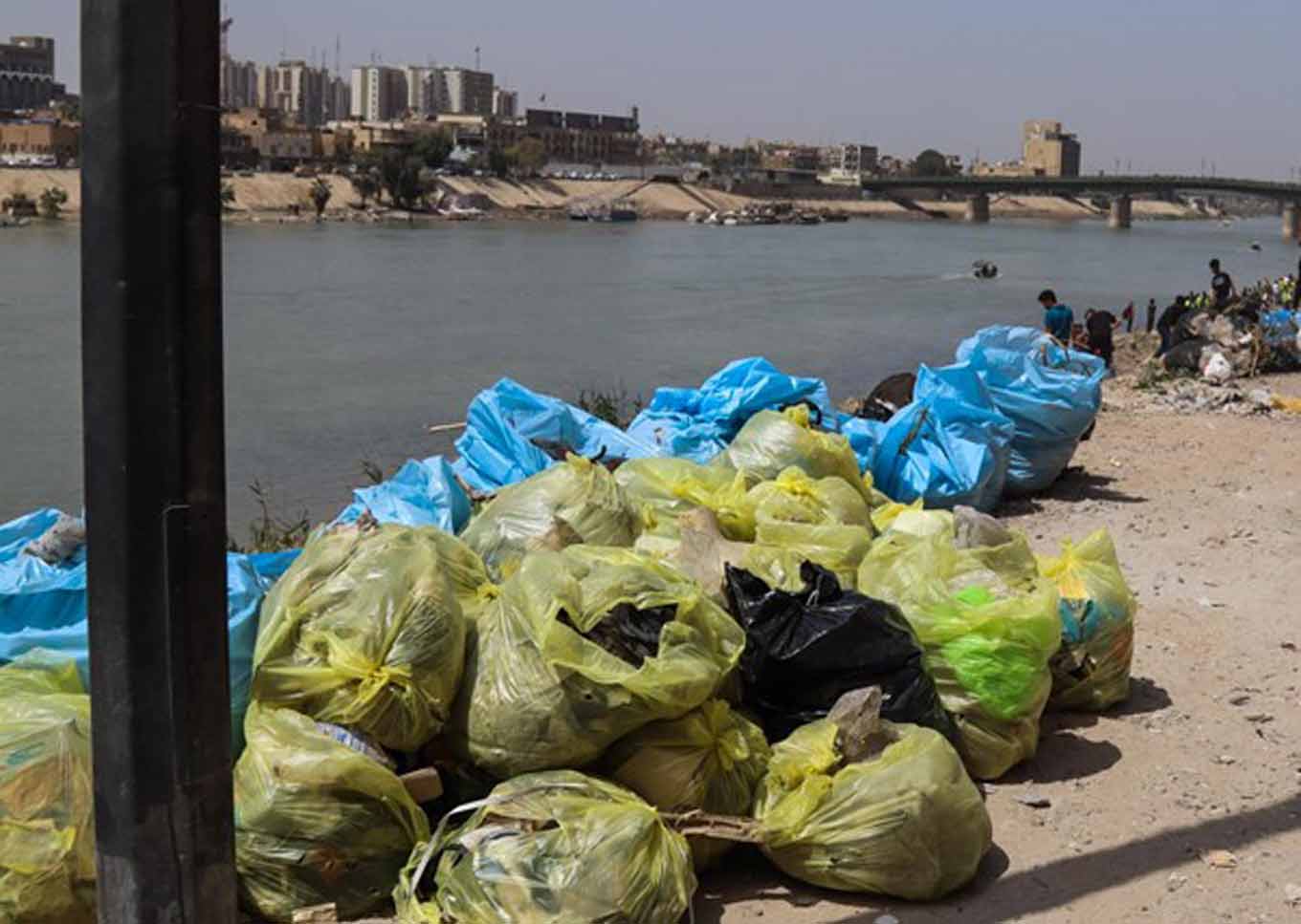 Gevulde vuilniszakken met de rivier de Tigris op de achtergrond