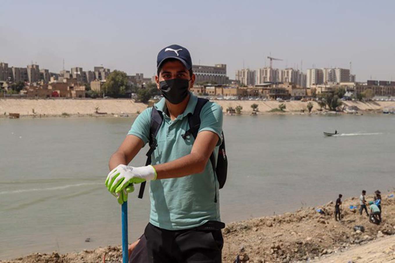 Een vrijwilliger die poseert voor de camera met de rivier de Tigris op de achtergrond