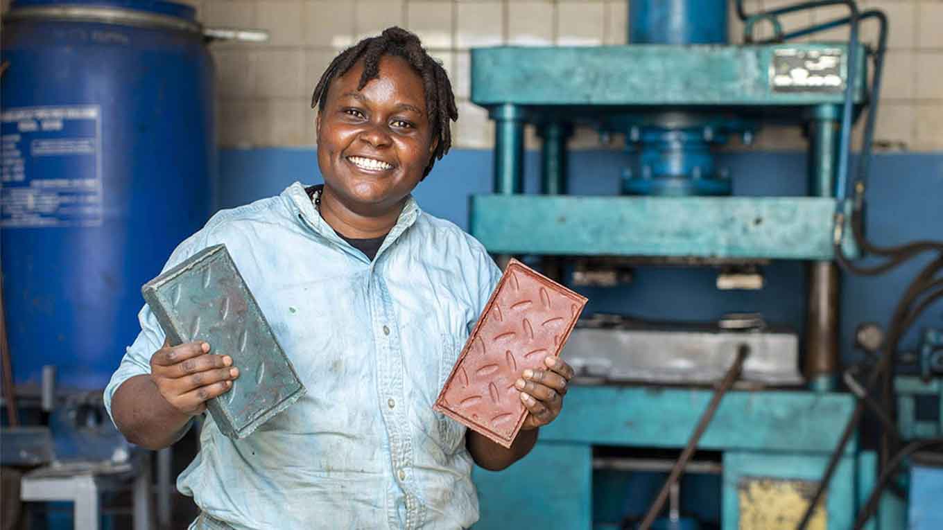 Keniaanse vrouw glimlacht en houdt kleurrijke stenen vast gemaakt van gerecycled plastic