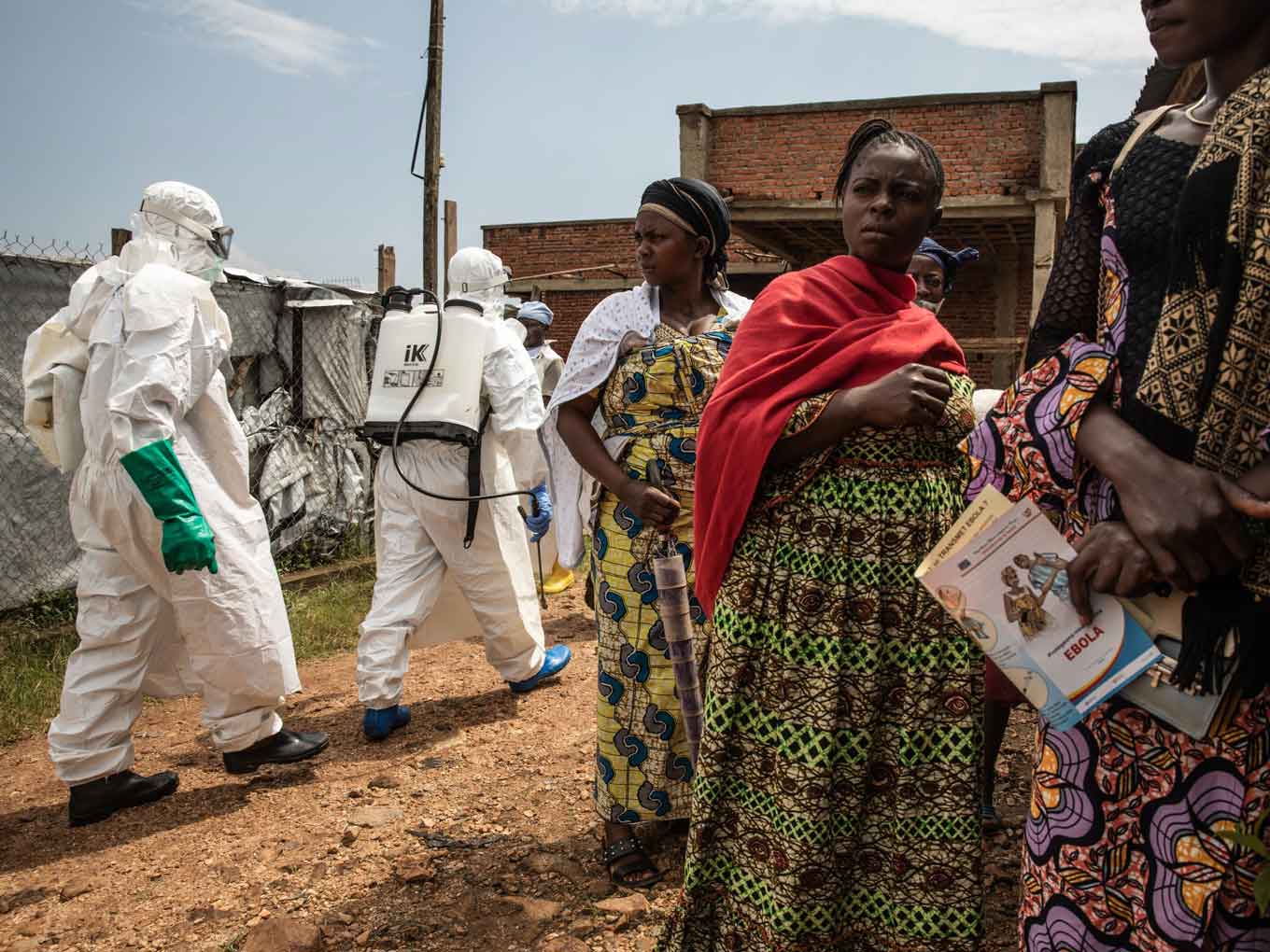 Noodhulpverleners in volledige beschermende pakken bereiden zich voor om het lichaam van een ebolaslachtoffer te verplaatsen terwijl leden van een groep overlevenden toekijken in Beni, Democratische Republiek Congo, 14 oktober 2021.