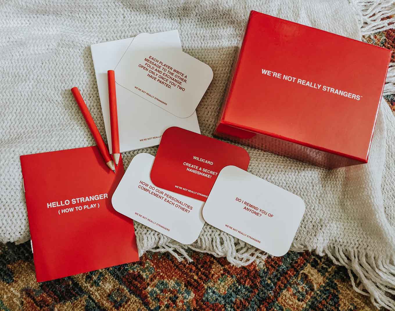 Rood-wit kaartspel met de tekst "We zijn niet echt vreemden" met een rood potlood en papier