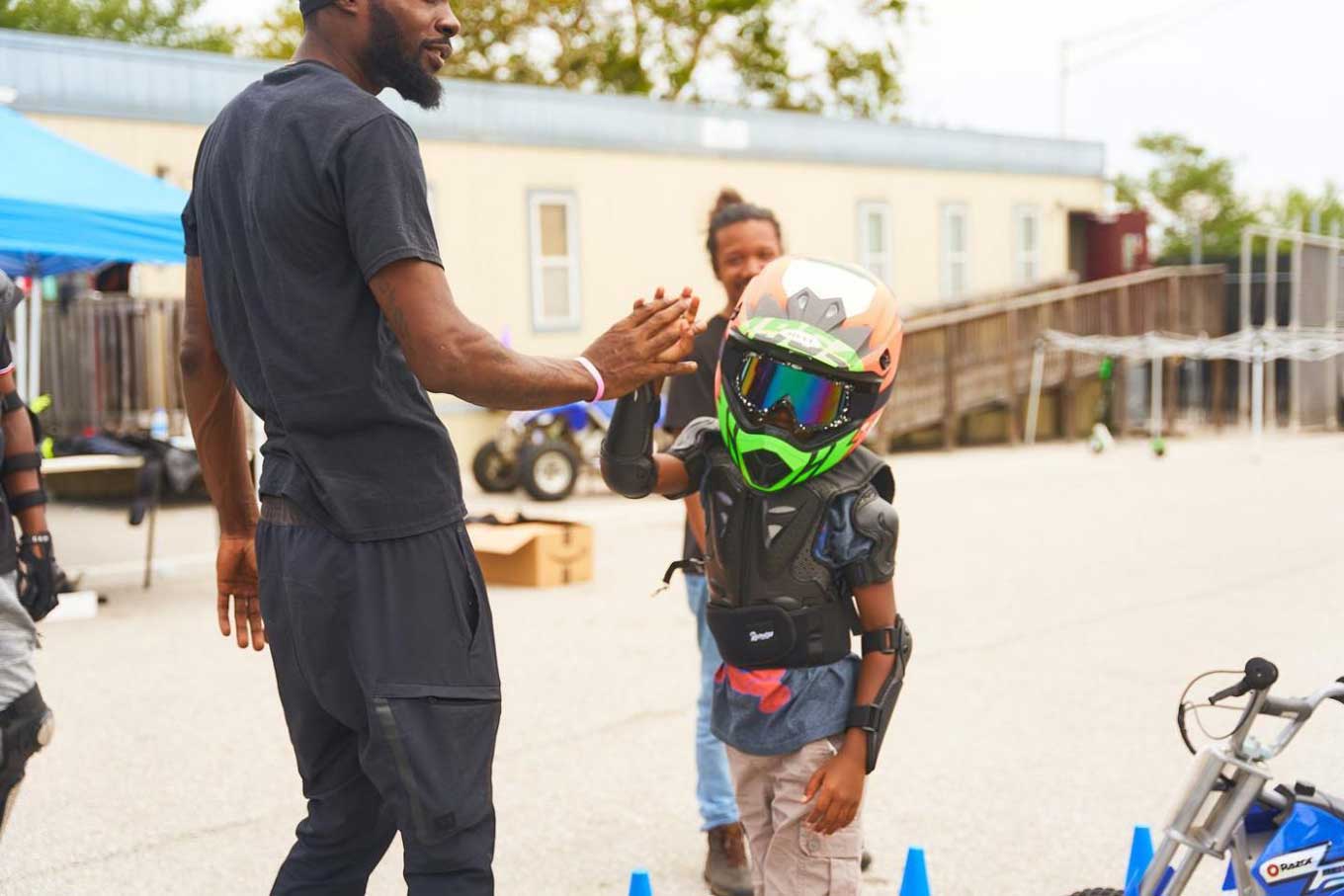 Een kind met een helm high fivet een man voor hem