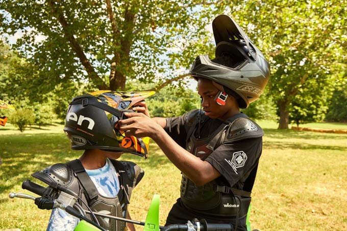 Een kind past de helm van een ander kind aan