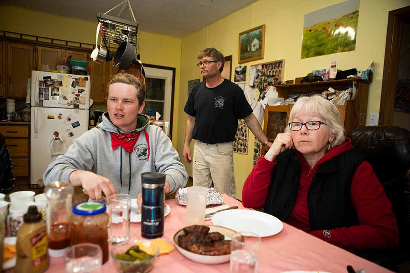 Zack en zijn moeder zitten op een tafel klaar om te eten terwijl ze luisteren naar iemand die achter de camera praat. Zijn vader zit achter hen beiden.