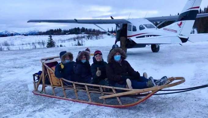 Medisch team in een slee, naast een klein vliegtuig, in Alaska