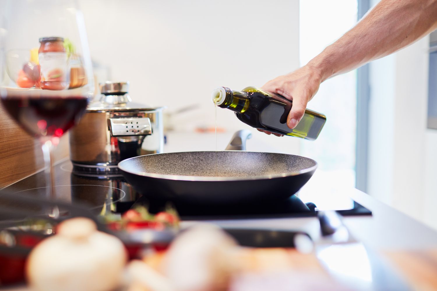 Close-up van mannelijke hand die olie in pan in de keuken giet