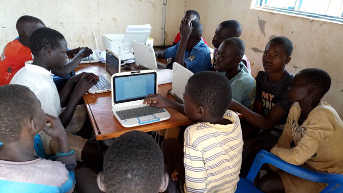 Studenten verzamelen zich rond computers tijdens ICT-training voor Zuid-Soedanese vluchtelingen in de West-Nijlregio in Noord-Oeganda. 