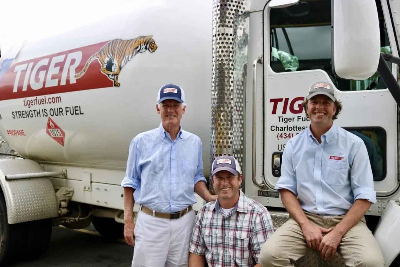 Drie mannen glimlachen eerder voor een brandstoftruck