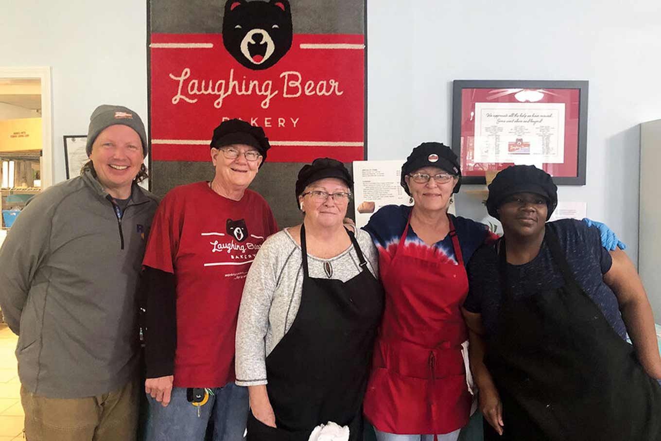 Medewerkers van de Laughing Bear Bakery poseren met een glimlach voor een groepsfoto