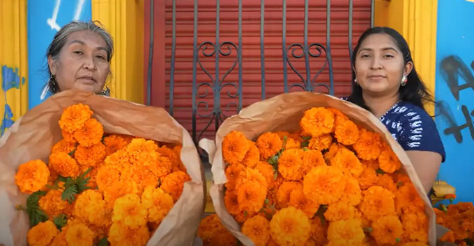 Een moeder en een dochter poseren met oranje bloemen