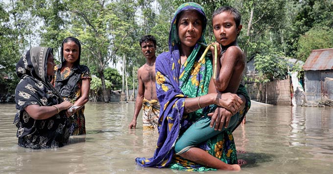 Een vrouw met haar kind en anderen, staand in taille-diep water