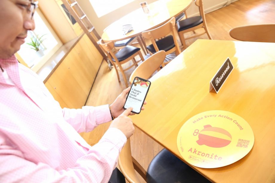 Een persoon toont tekst op zijn telefoon over zijn restaurant, in een restaurant