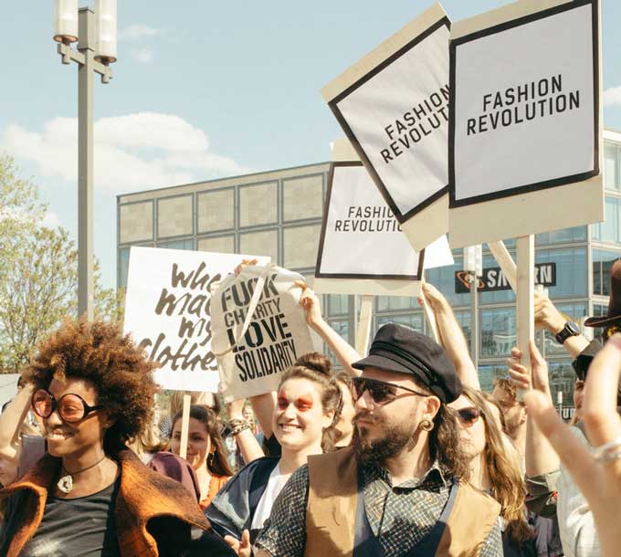 Mensen op straat die borden vasthouden met de tekst "Moderevolutie" en "Fuck Liefdadigheid Liefde Solidariteit"