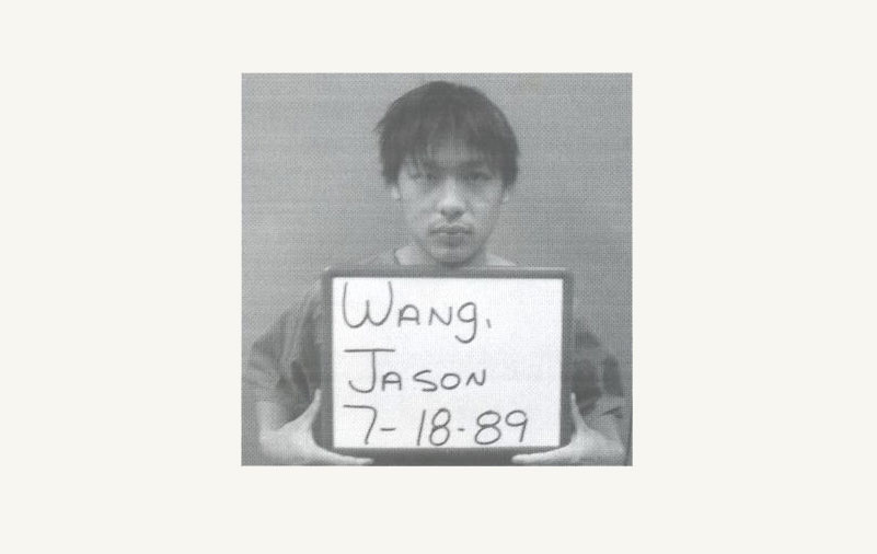 Jason Wang's gevangenis mugshot - met een bord met zijn naam en verjaardag erop