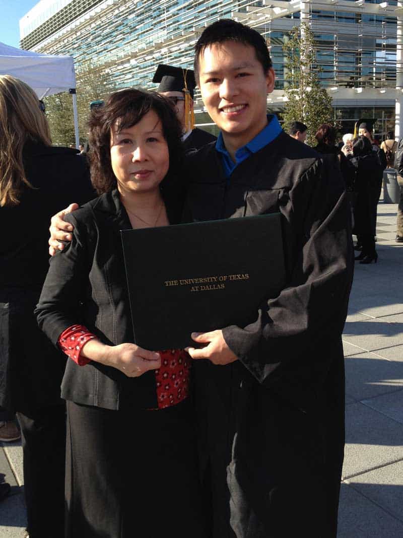 Jason Wang met zijn moeder poseert buiten in een pet en jurk terwijl hij een diploma heeft dat zegt De Universiteit van Texas in Dallas