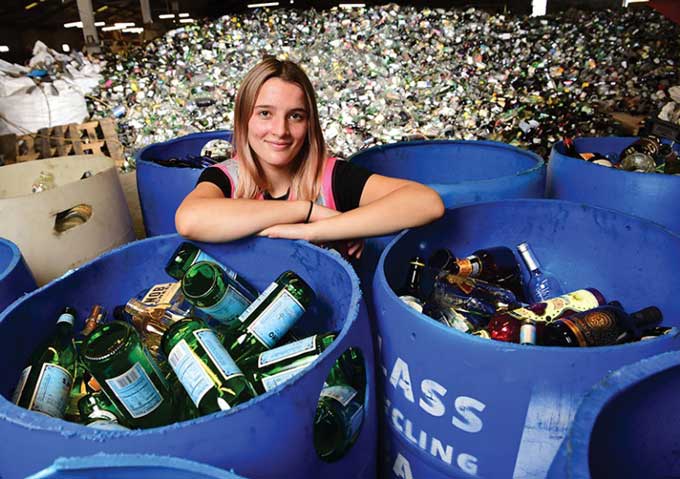 Franziska Trautmann poseert met een magazijn vol glazen flessen voor recycling