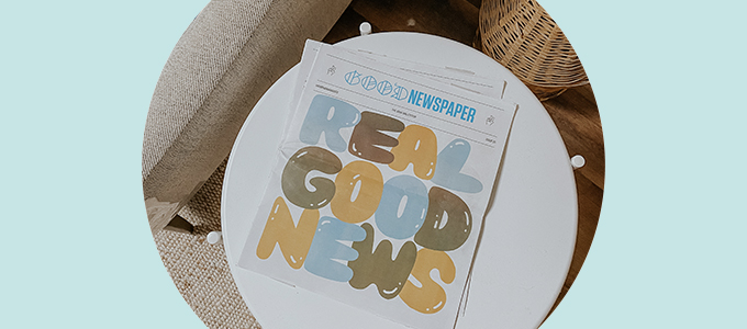 Overheadfoto van het Goodnewspaper zittend op een bijzettafeltje. Op de cover staat 'Echt Goed Nieuws."