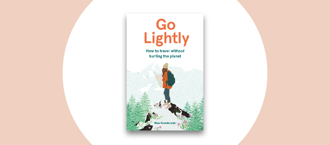De cover van het boek "Ga licht: Hoe te reizen zonder de planeet pijn te doen." De cover heeft een tekening van een vrouw die een rode jas, muts en rugzak draagt met een kaart. Ze staat op een bergtop met bomen om haar heen.