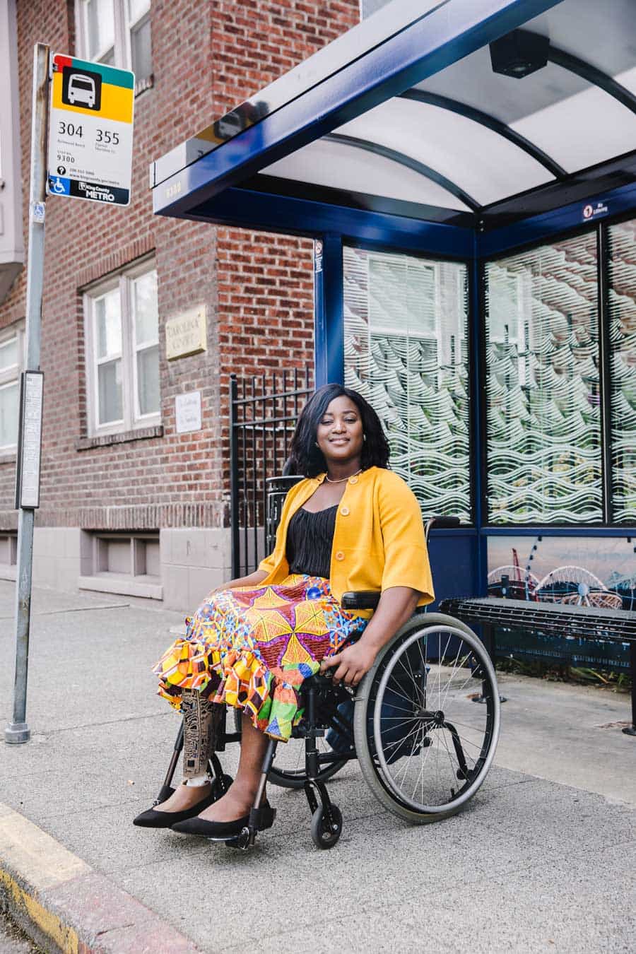 Een zwarte vrouw in een rolstoel wacht op de bus bij een bushalte in de seattle metro area