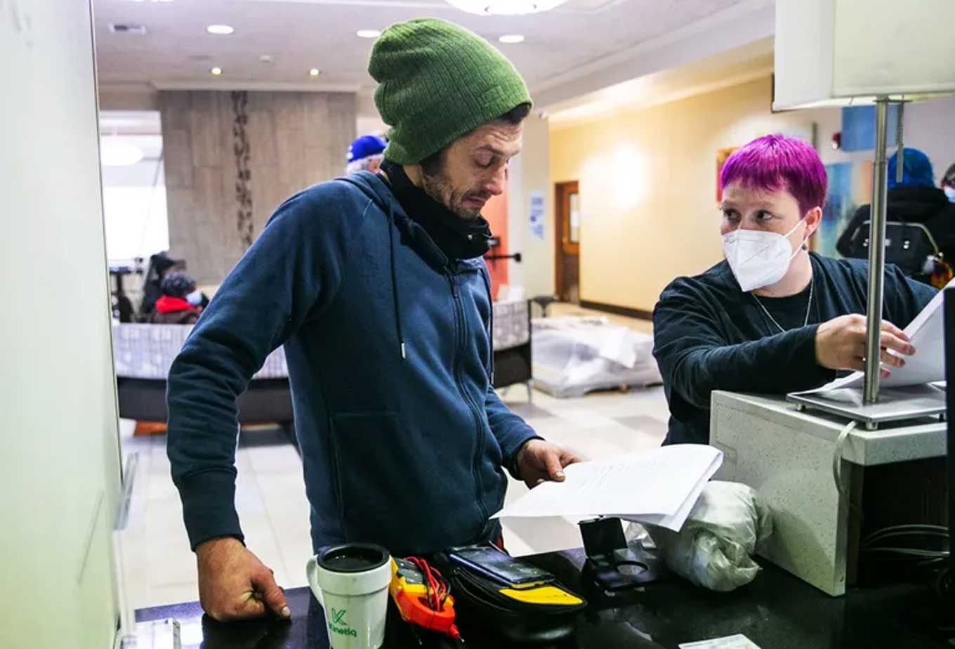 Gonzo controleert papierwerk dat in een van zijn handen wordt gehouden terwijl een hotelmedewerker hem aankijkt.