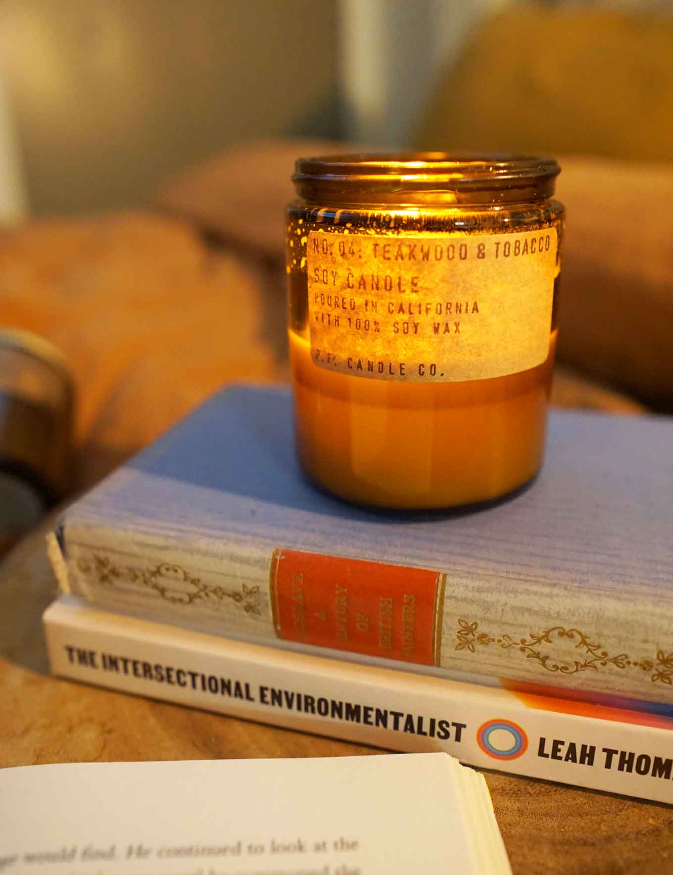 Brandende kaars met een label dat nr. 04 zegt: Teakwood &Tobacco, Soy Candle, Poured in California with 100% soy wax, P.F. Candle Co