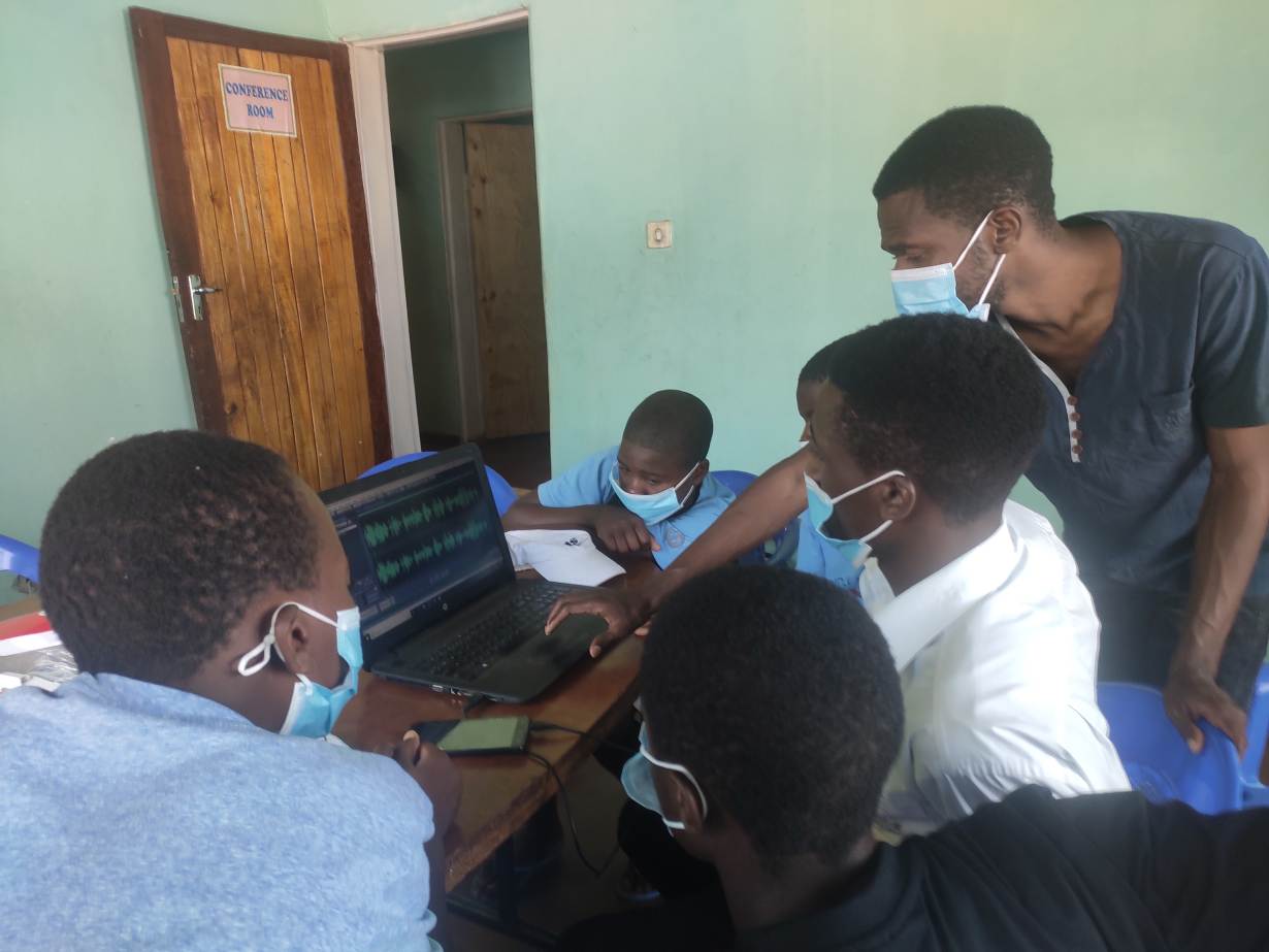 Een groep jongeren in Malawi bewerkt hun radioshow op een laptop