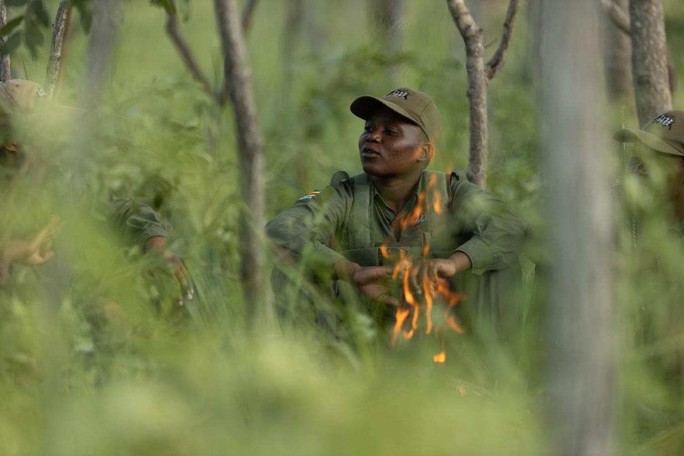 Een ranger zit terwijl hij wordt omringd door een bos