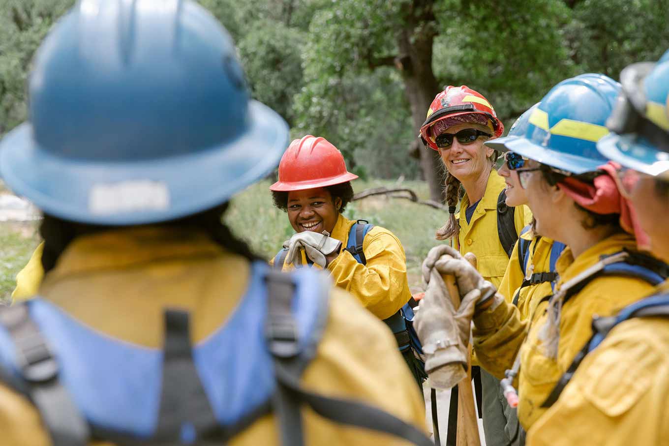 Tricia en een andere vrouwelijke brandweerman glimlachen met meer brandweerlieden om hen heen