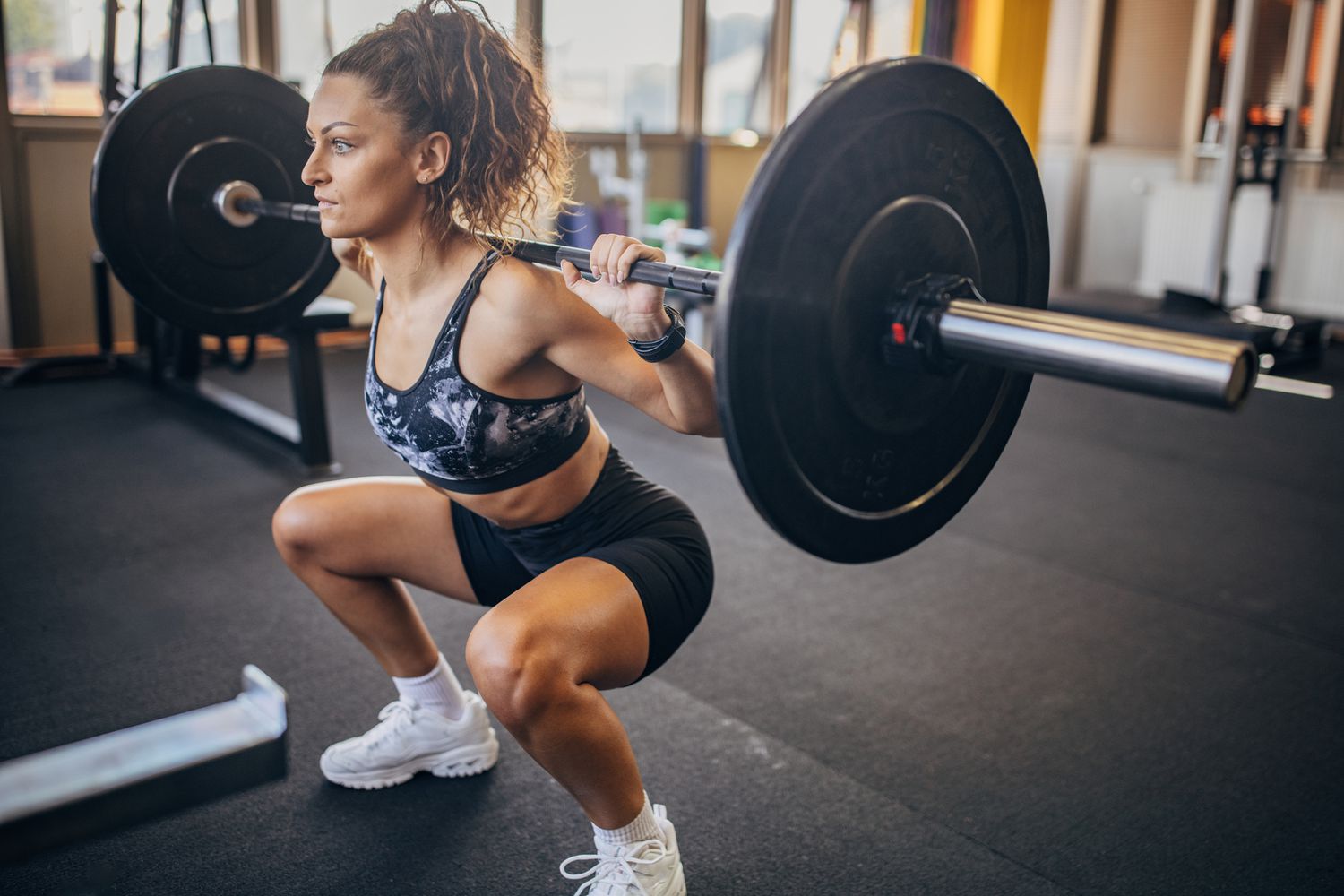 vrouw die de barbell squat uitvoert