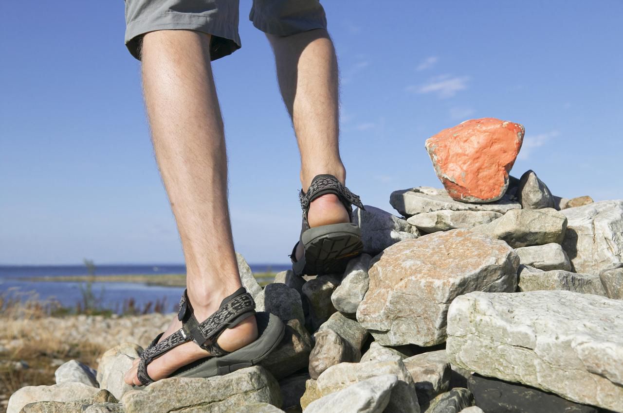 Mannenvoeten in sandalen die bovenop rots pilo staan