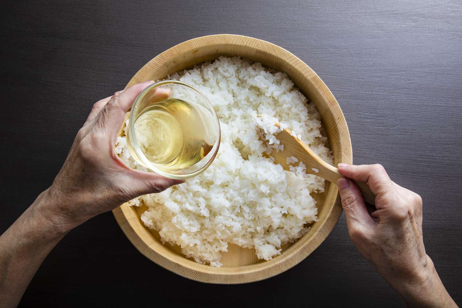 Rijstazijn in een kom witte rijst gieten
