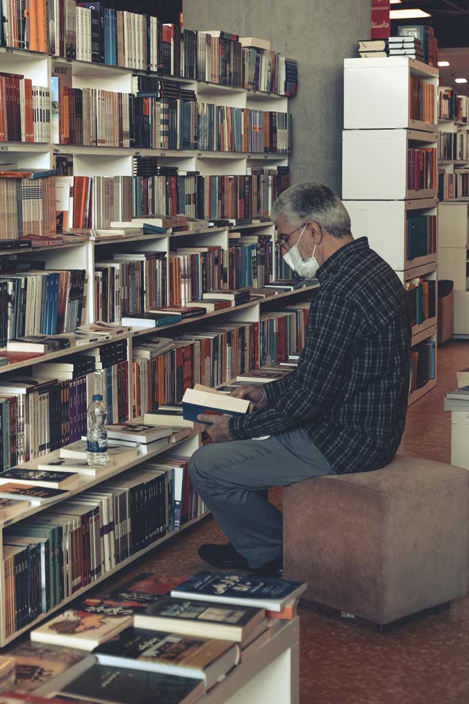 Een man draagt een masker in een bibliotheek