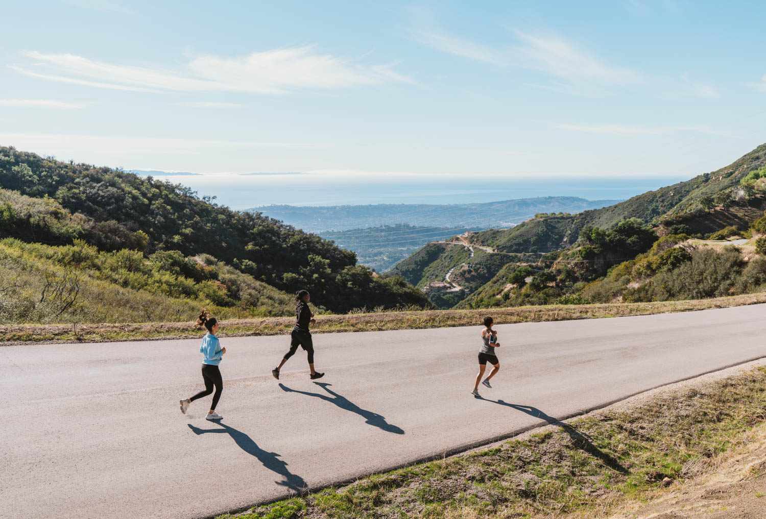 drie hardlopers die bergafwaarts joggen op de bergweg
