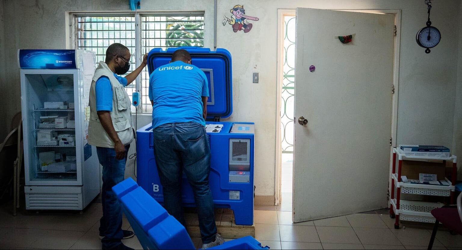 Twee mannen gebruiken een innovatieve blauwe koelkast om vaccins koud en veilig te houden 