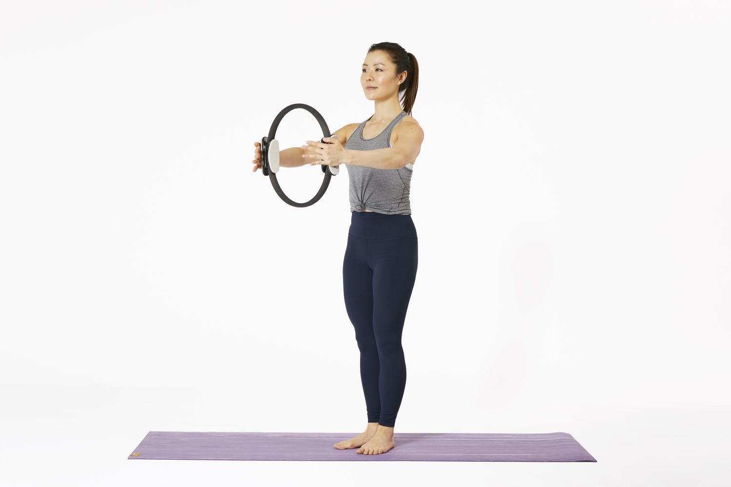 Vrouw die op yogamat staat met Pilates Magic Circle