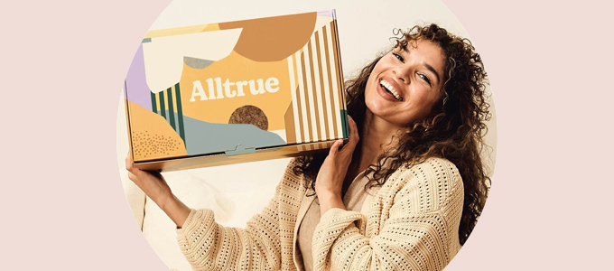 Een vrouw glimlacht en houdt een Alltrue-abonnementsdoos omhoog.