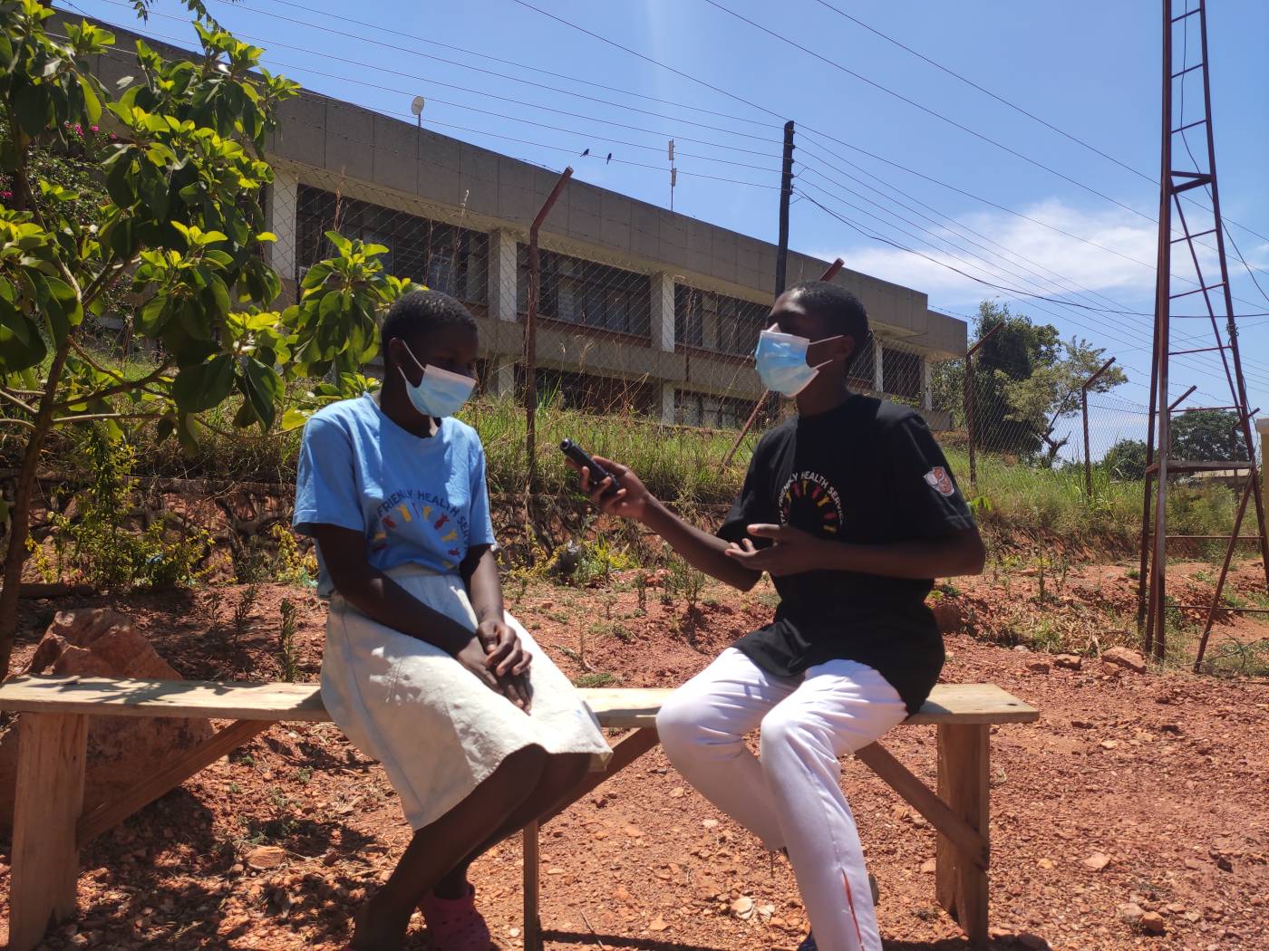 Twee tieners in Malawi zitten op een bankje om een radio-interview op te nemen
