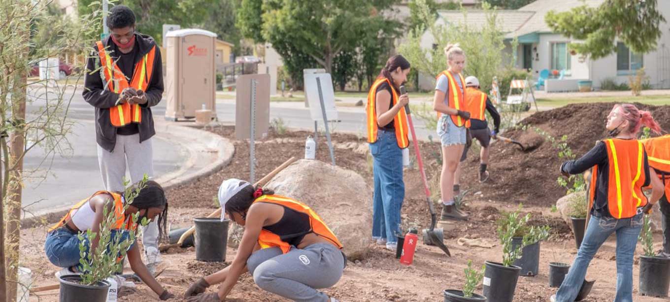 Een groep jeugdactivisten draagt oranje hesjes en werkt aan een milieuproject