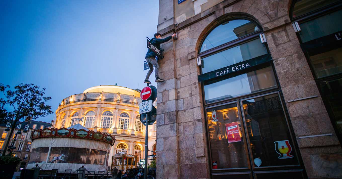 Een parkour-acrobaat beklimt een bord om een lichtschakelaar op een gebouw om te draaien