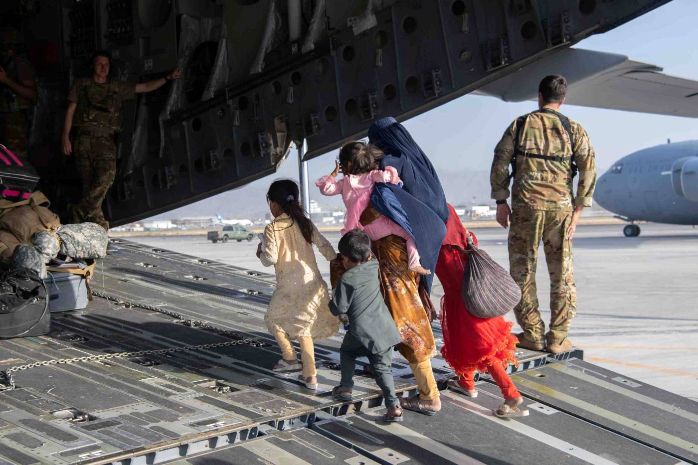 Een familie Afghaanse vluchtelingen stapt aan boord van een militair vliegtuig