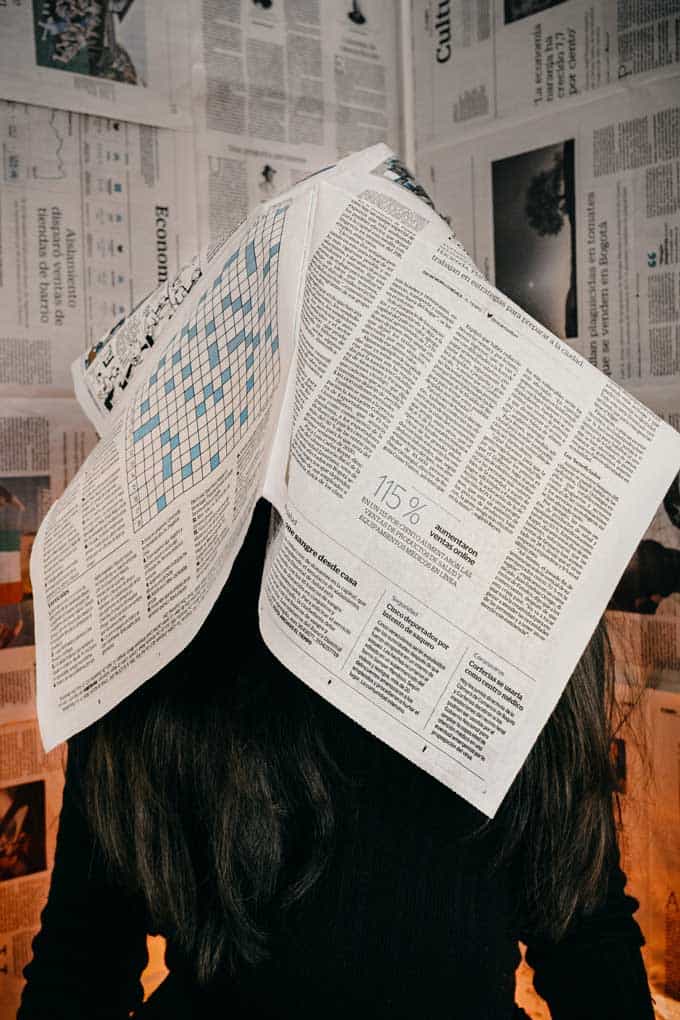 Iemand heeft een krant boven zijn hoofd omdat hij overweldigd is door het nieuws