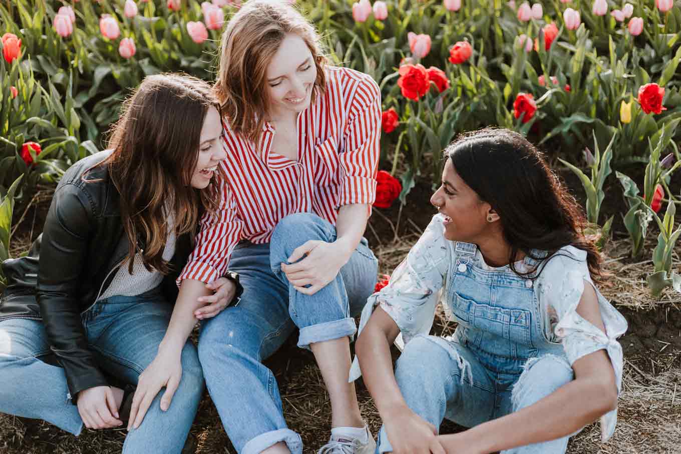 Drie vrienden glimlachen en lachen in een veld met bloemen