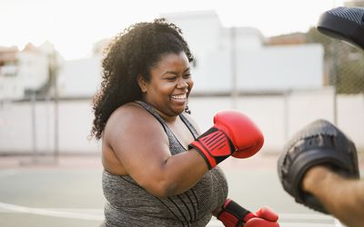 Afrikaanse curvy vrouw en personal trainer die bokstrainingssessie buiten doet - Focus op gezicht