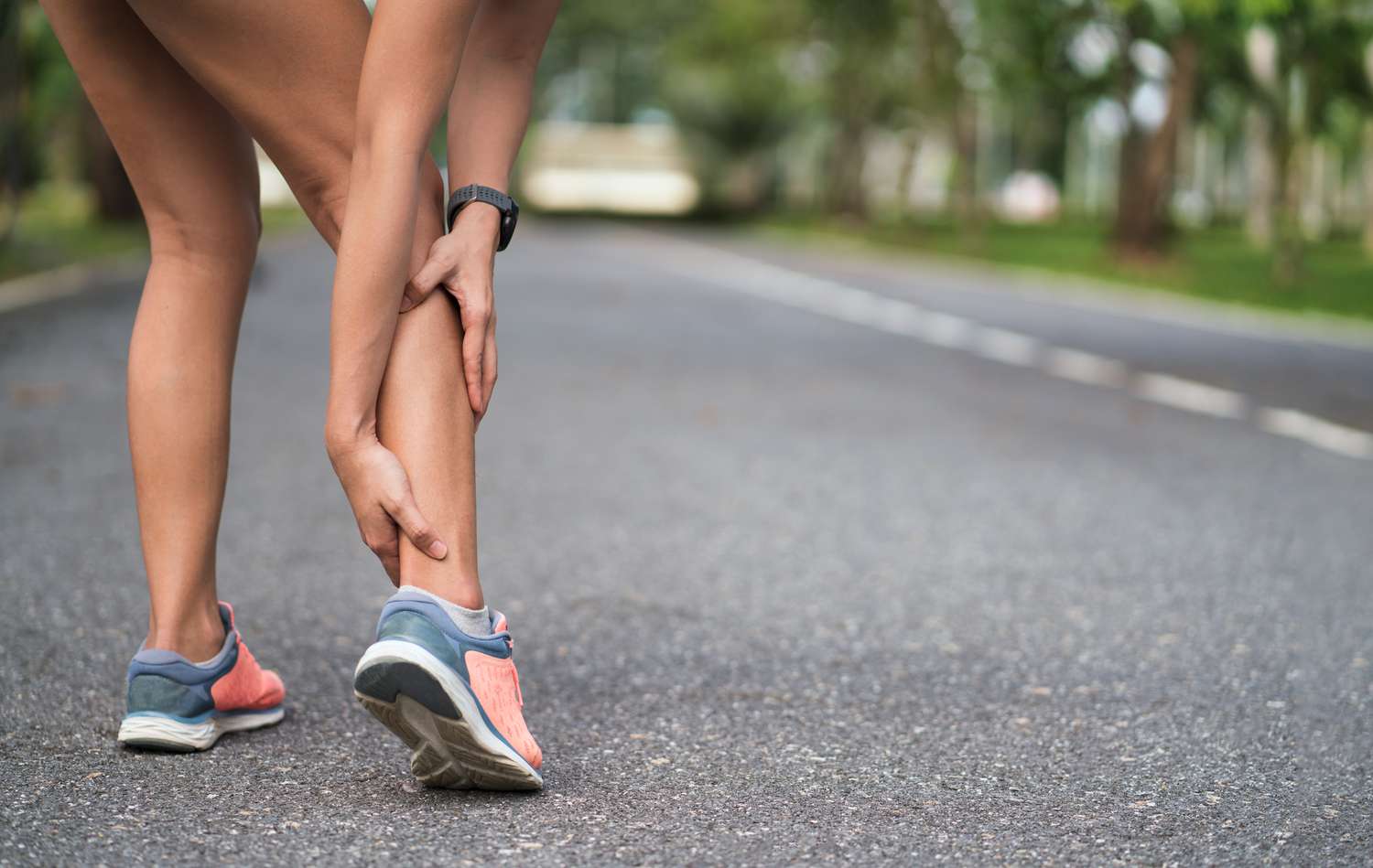 Achillesblessure bij het buiten lopen. Vrouwen die achillespees met de handen dicht bij elkaar houden en lijden aan pijn. Enkeldraai verstuiking ongeval bij sportoefening hardlopen joggen.