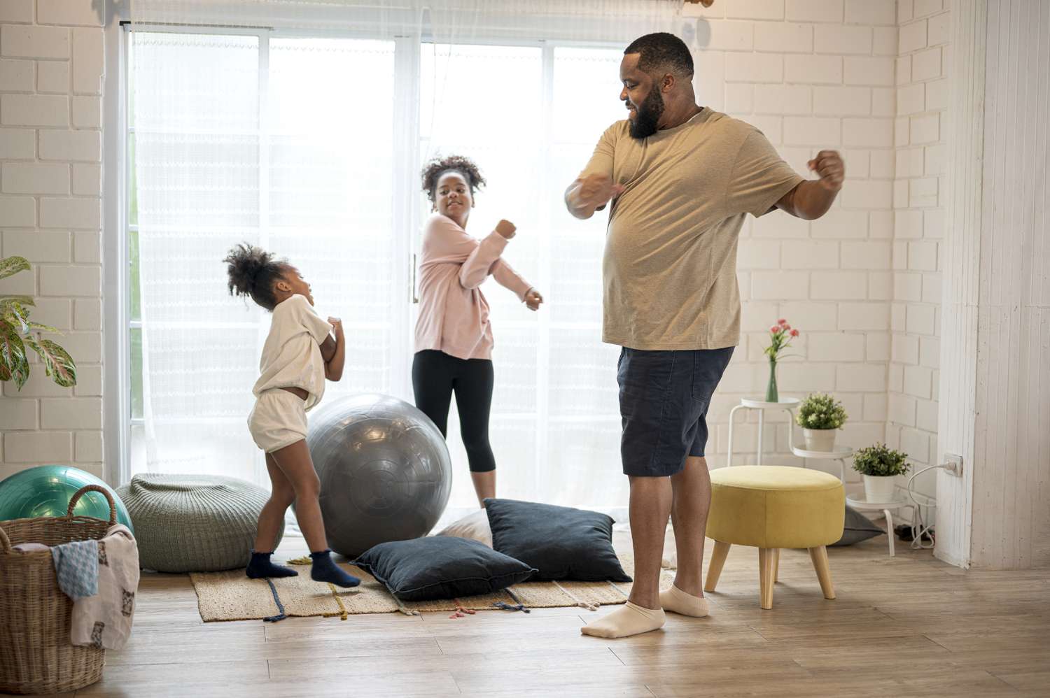 Afro-Amerikaanse vader en zijn twee dochters sporten 's ochtends thuis.