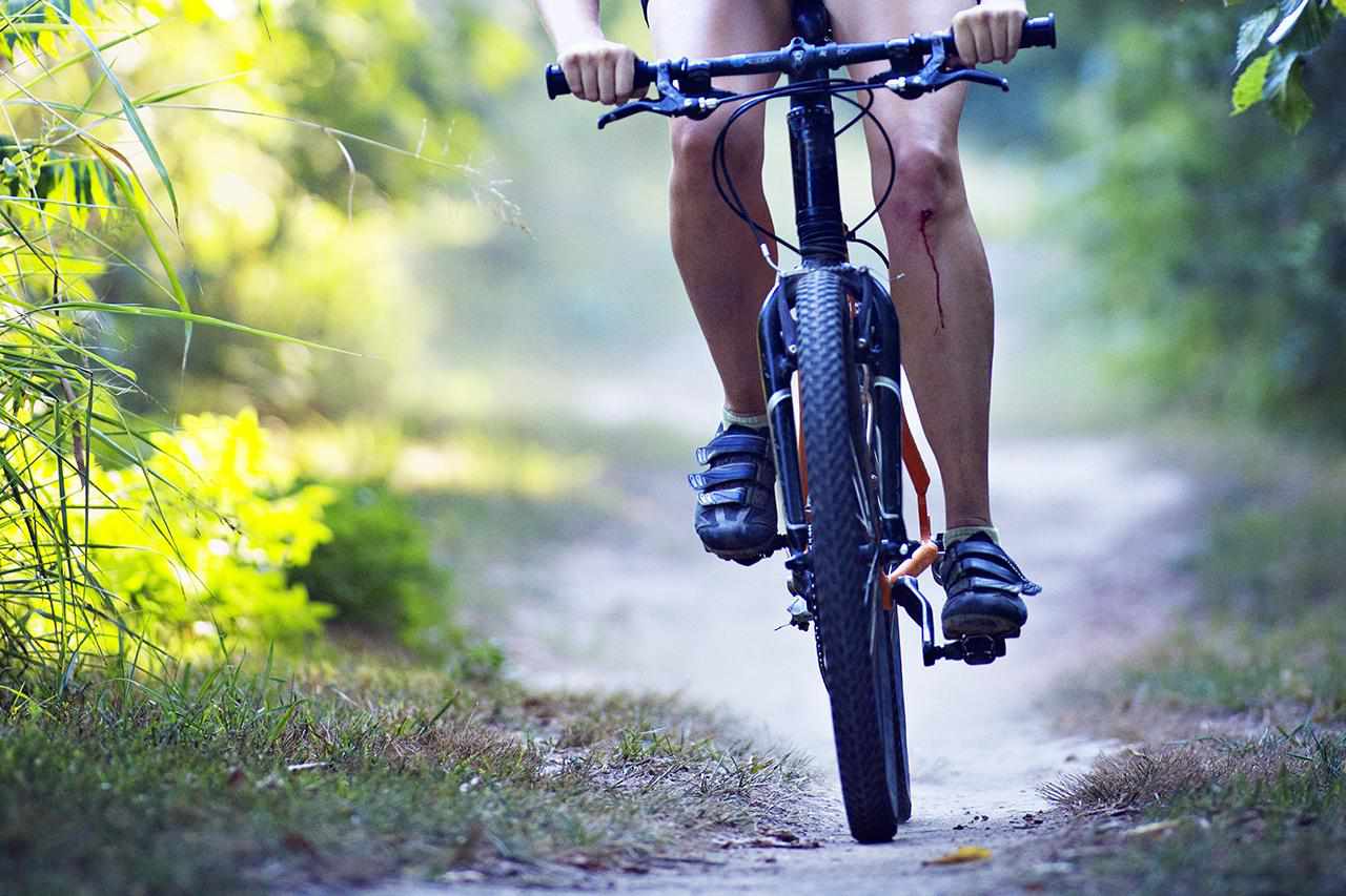 Vrouw met bebloede knie rijdende fiets