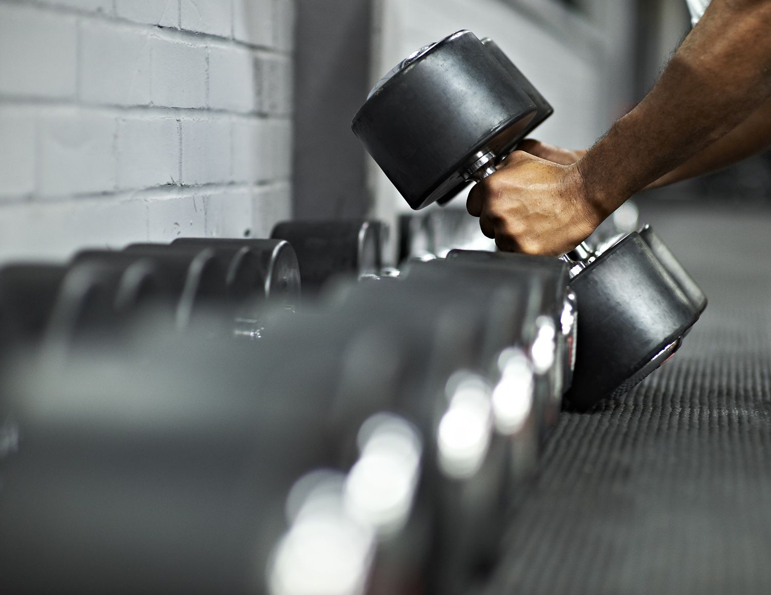 Atletische man die dumbbells oppakt in gym